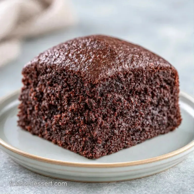 Part de g&acirc;teau sombre sur assiette blanche, accompagn&eacute;e d'une cr&egrave;me onctueuse et d'une framboise rouge &eacute;clatante.