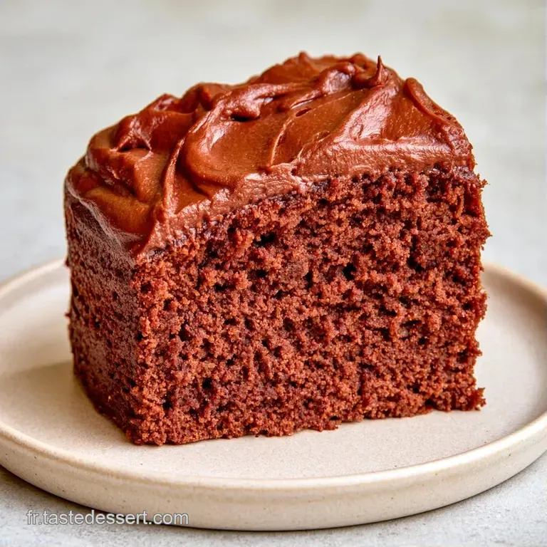 Part de g&acirc;teau au chocolat fondant sur une assiette blanche, accompagn&eacute;e d'une baie rouge et d'une feuille de menthe.